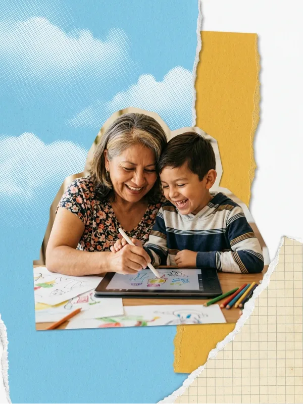 A grandmother and her grandson laughing as they draw together on a tablet