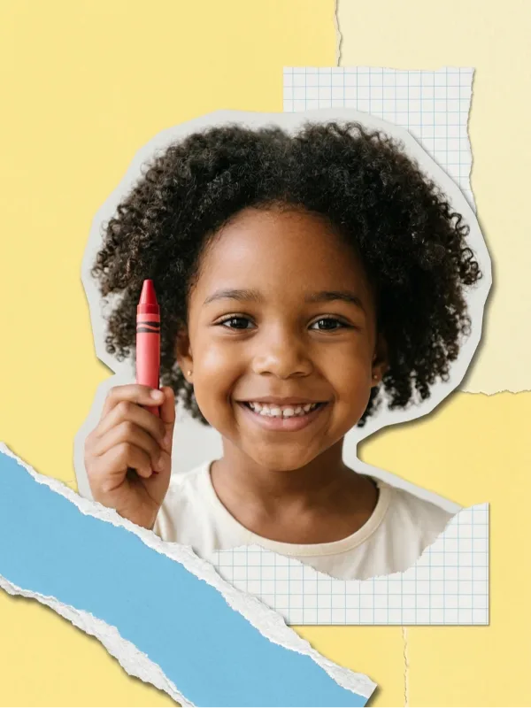 A smiling girl holding up a red crayon, on a collage of yellow paper and graph paper